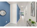 Long hallway featuring white tile flooring, blue accent wall, and decorative wall art at 2009 Tropical Palms Cir, Kissimmee, FL 34747