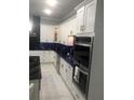 Modern kitchen boasts white cabinetry, black marble countertops, and stainless steel appliances at 2300 Painter Ln, Kissimmee, FL 34741