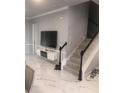 Bright living room featuring elegant marble floors, staircase, and modern floating entertainment center at 2300 Painter Ln, Kissimmee, FL 34741
