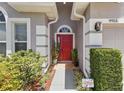 Inviting entryway features a red front door, tiled floor, manicured landscaping, and stylish exterior lighting at 9915 Kona Isle Ct, Orlando, FL 32817