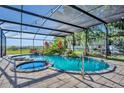Screened-in pool area with hot tub, stone waterfall, tropical plants, brick pavers and a scenic view at 1003 Shore Dr, Kissimmee, FL 34744