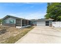 A charming single-story home with blue siding, brick accents, solar panels, a screened lanai, and an attached two-car garage at 1328 Laurel Dr, Daytona Beach, FL 32117