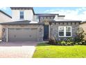Charming two-story home featuring stone accents, a brick driveway, a two-car garage and well-manicured lawn at 1539 Wynell St, St Cloud, FL 34771