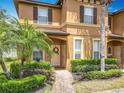 Close-up of a tan townhome with manicured shrubbery leading to an inviting entryway at 2744 Calabria Ave, Davenport, FL 33897