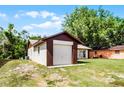 View of the detached garage with white door featuring brick trim, set in a grassy yard at 288 Howard Blvd, Longwood, FL 32750