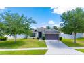 Inviting single-story home featuring a green lawn, mature trees, and a convenient two-car garage at 337 Giovani Blvd, Clermont, FL 34715