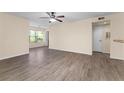 Bright living room with wood-look flooring, ceiling fan, and natural light through a large window at 5112 Conroy Rd # 13, Orlando, FL 32811