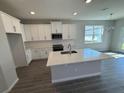 A modern kitchen featuring white cabinets, stainless steel appliances, gray flooring, and a large island at 652 Pothos St, Apopka, FL 32703