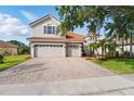 View of the home's facade showing the three-car garage, brick-paved driveway, and manicured lawn at 11508 Delwick Dr, Windermere, FL 34786
