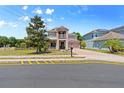 Two-story home with a neutral color scheme, balcony, well-kept lawn, and brick-paved driveway at 1204 Lexington Ave, Davenport, FL 33837
