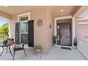 Inviting front porch area with chair and table arrangement, plants, and a view of the home's entryway at 1204 Lexington Ave, Davenport, FL 33837