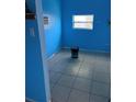 A bright blue small room with one window, tiled flooring, and an air conditioning unit at 1231 Leon Ln, Daytona Beach, FL 32117