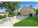 Home's exterior showcasing a lush lawn, extended driveway leading to a two-car garage, and well-maintained landscaping at 14208 Morning Frost Dr, Orlando, FL 32828