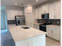 Modern kitchen with white cabinetry, a large island with sink, and sleek stainless steel appliances for cooking at 14746 Erice Ave, Clermont, FL 34714