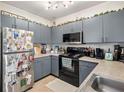 Well-lit kitchen featuring gray cabinets, laminate countertops, stainless steel fridge and black appliances at 206 E South St # 3008, Orlando, FL 32801