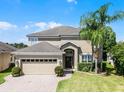 Inviting two-story home with a lush green lawn, brick driveway, and beautiful landscaping at 2411 Sabastian St, Mount Dora, FL 32757