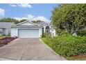 Inviting home featuring a two-car garage, well-maintained lawn, and a peaceful residential setting at 25057 Riverwalk Dr, Leesburg, FL 34748