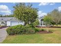 Beautifully landscaped front yard featuring lush greenery, mature trees, and a well-maintained lawn at 25057 Riverwalk Dr, Leesburg, FL 34748