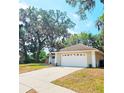 Attached garage of the home with a concrete driveway surrounded by manicured landscaping with mature trees at 513 Rachael Ct, Oviedo, FL 32765