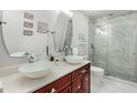 Modern bathroom with double bowl sinks, cherry cabinets, quartz countertop, and a walk-in glass shower at 555 Carey Way, Orlando, FL 32825