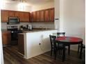 Eat-in kitchen with stainless steel appliances, wood cabinets, and a black table and chairs at 6117 Metrowest Blvd # 106, Orlando, FL 32835