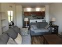 Open-concept living room with couches, wood floors, and a kitchen with tile backsplash at 6117 Metrowest Blvd # 106, Orlando, FL 32835
