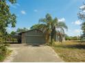 Attached garage with stone accents and a concrete driveway amidst lush greenery and palm trees at 8735 Rancho Ct, Orlando, FL 32836