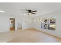 Spacious living room with light wood floors, a ceiling fan, and views of the front yard at 3111 Pine Tree Dr, Edgewater, FL 32141