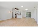 Bright open-concept living room featuring light wood floors, modern lighting fixtures, and access to the kitchen at 3111 Pine Tree Dr, Edgewater, FL 32141