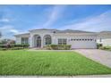 Well-maintained home featuring a pristine lawn, attractive arched entryway, and a two-car garage at 409 Belfry Dr, Davenport, FL 33897