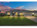 Charming home with manicured lawn and arched entry, illuminated by the warm glow of sunset at 409 Belfry Dr, Davenport, FL 33897
