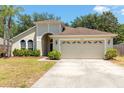 Single-story home boasting an attached two-car garage, and a front lawn with beautiful greenery at 830 Grand Hughey Ct, Apopka, FL 32712