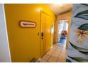Bright hallway with yellow walls, tile flooring, and decorative accents and views of the main living areas at 1671 Judith Dr, Kissimmee, FL 34758