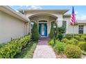 Close up view of a home's arched entryway with a bright blue front door and landscaped walkway at 224 Bluestone Pl, Casselberry, FL 32707