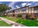 Stylish Tudor-style condo building featuring lush green lawn, brick accents and inviting walkway at 5325 Hansel Ave # E-15, Orlando, FL 32809