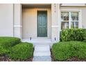 Close-up of the townhome's entrance with a dark green door, landscaped bushes, and clean concrete steps at 6013 Blue Lily Way, Winter Garden, FL 34787