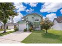 Inviting two-story home with a well-manicured lawn, concrete driveway, and attached garage at 645 Upperriver Ct, Orlando, FL 32828