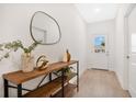 Bright entryway with light wood floors, a stylish console table, a decorative mirror, and a white front door with a window at 9472 Se 152Nd Pl, Summerfield, FL 34491
