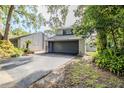 Inviting exterior showcasing a gray two-car garage, lush landscaping, and paved driveway at 121 Primrose Dr, Longwood, FL 32779