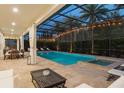 Relaxing screened-in pool and spa with travertine tile, palm trees, and outdoor dining area at 8017 Chilton Dr, Orlando, FL 32836