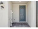 Covered entryway featuring a gray front door, wall-mounted light fixture and brick pavers at 16419 Bird Of Paradise Ave, Clermont, FL 34714