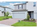 Charming two-story home with gray siding, a two-car garage, and brick paver driveway at 16430 Bird Of Paradise Ave, Clermont, FL 34714