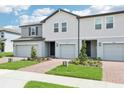 New townhouses with light gray and dark gray accents featuring manicured lawns and brick paver driveways at 16434 Bird Of Paradise Ave, Clermont, FL 34714