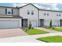 Row of new construction townhouses with manicured lawns, brick paved driveways, and gray exterior paint at 16434 Bird Of Paradise Ave, Clermont, FL 34714