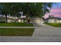 Charming single-story home featuring a well-manicured lawn, mature trees, and attached two car garage at dusk at 360 Coventry Estate Blvd, Deltona, FL 32725