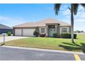 Charming single-story home with a well-manicured lawn, three-car garage, and welcoming entryway at 829 Terranova Rd, Winter Haven, FL 33884
