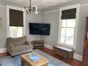 Comfortable living room with hardwood floors, gray walls, large windows, and a flatscreen television at 209 E 4Th St, Sanford, FL 32771