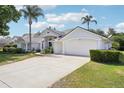 Spacious driveway leading to a three-car garage, with a well-maintained lawn and tropical landscaping at 336 Plantation Club Dr, Debary, FL 32713
