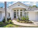 Elegant home entrance featuring a decorative wreath, arched windows, and lush landscaping enhancing curb appeal at 336 Plantation Club Dr, Debary, FL 32713