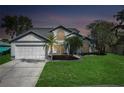 Charming two-story home featuring a well-manicured lawn, mature trees, and a spacious two-car garage at dusk at 11160 Sylvan Pond Cir, Orlando, FL 32825